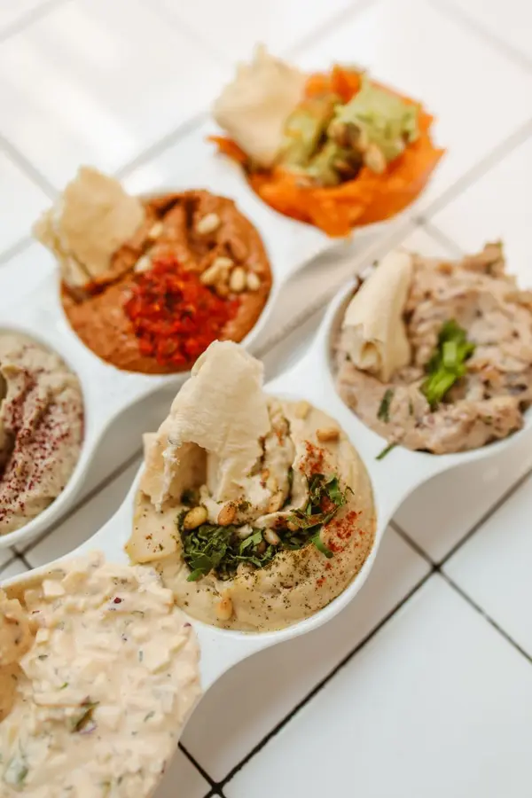Variety of hummus dips in serving bowls with pita