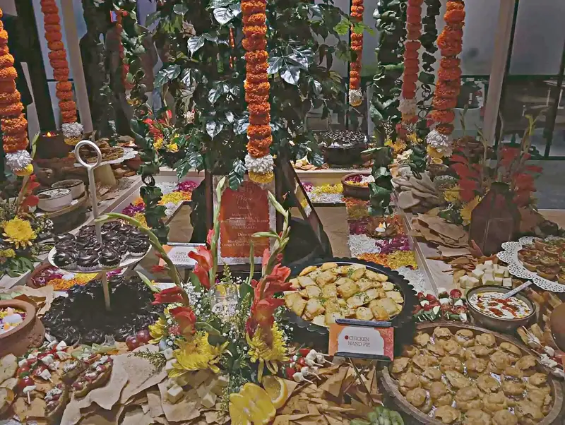 Large-scale festive buffet spread with marigold garlands and dozens of dishes