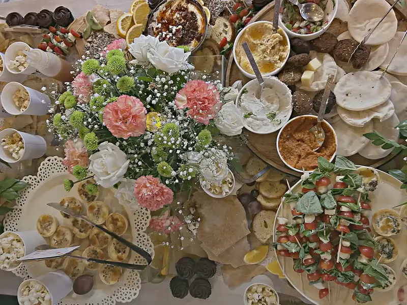 Overhead view of a Mediterranean spread with pink carnations and caprese skewers